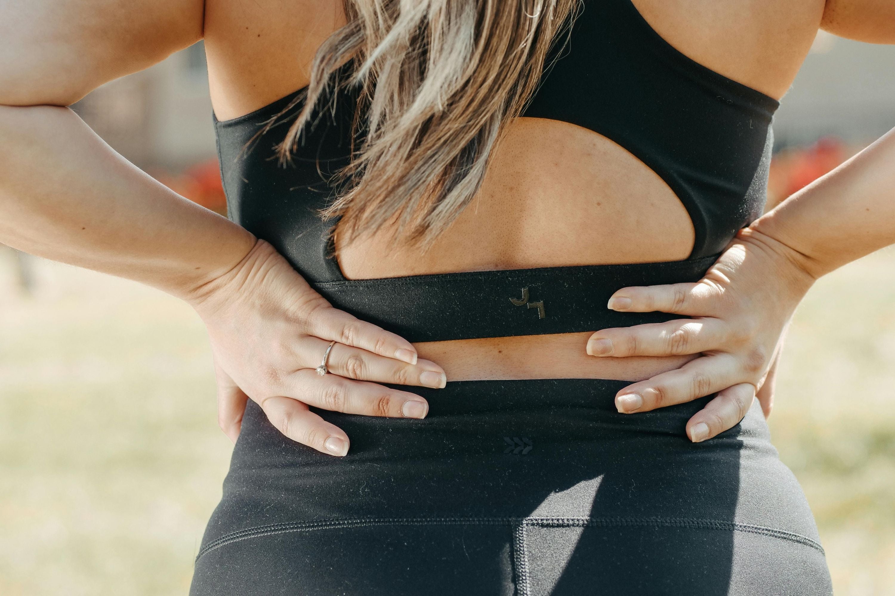 a woman holding her lower back hurt from wearing a weighted vest