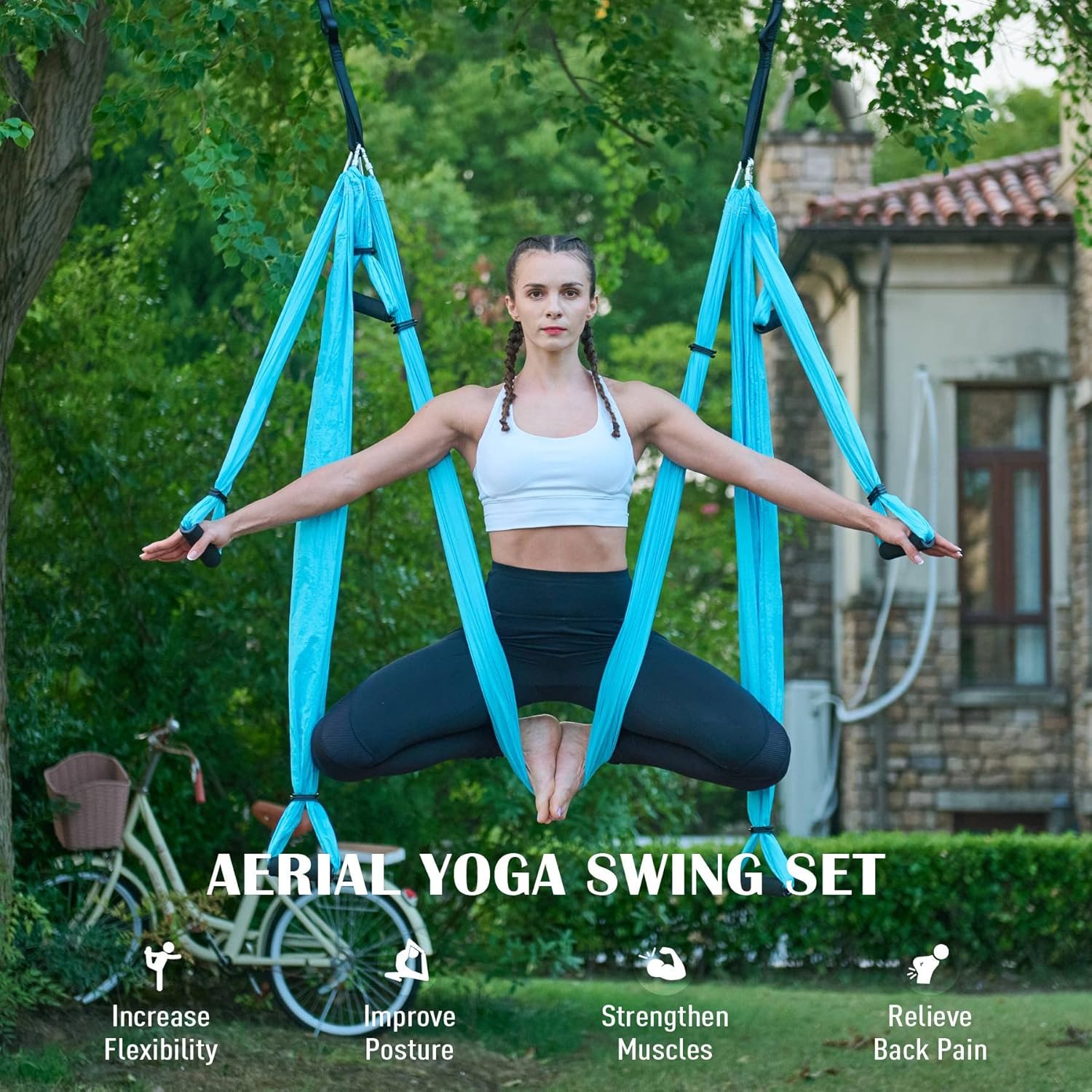 Woman using an aerial yoga swing set in a garden.