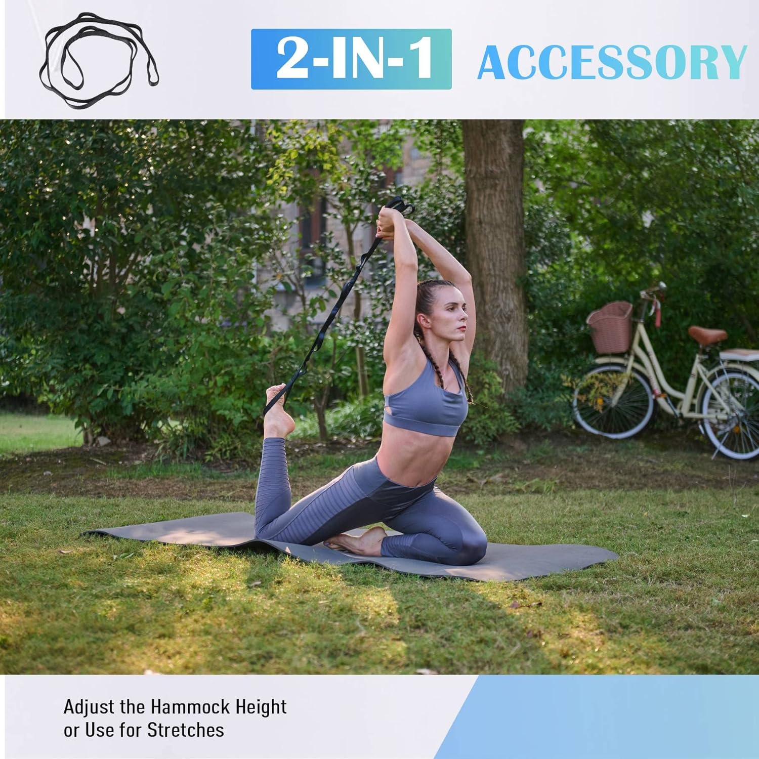 Woman using a yoga strap in a park with a bicycle in the background.