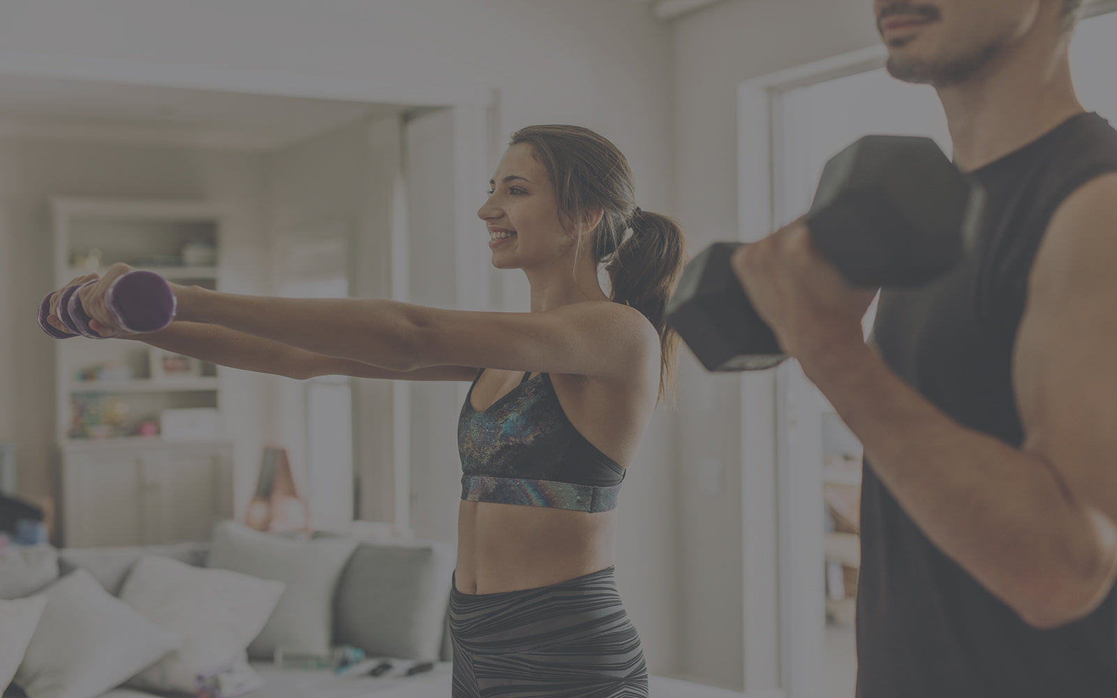 woman and man standing up lifting weights in living room