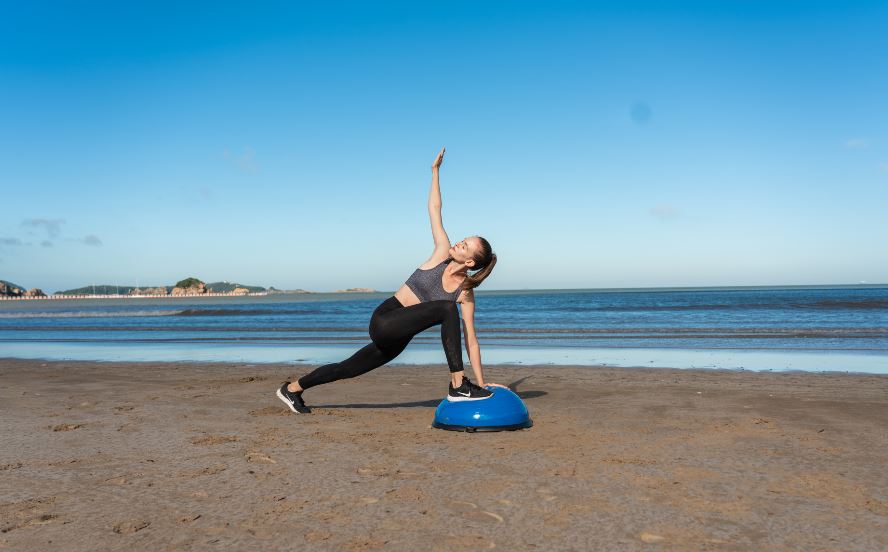 woman doing a yoga pose on a half balance ball